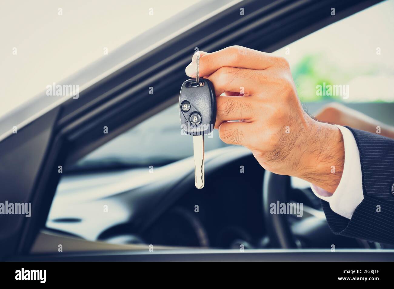Mano che tiene una chiave di automobile - vendita dell'automobile & concetto di affari di noleggio, tono vintage Foto Stock
