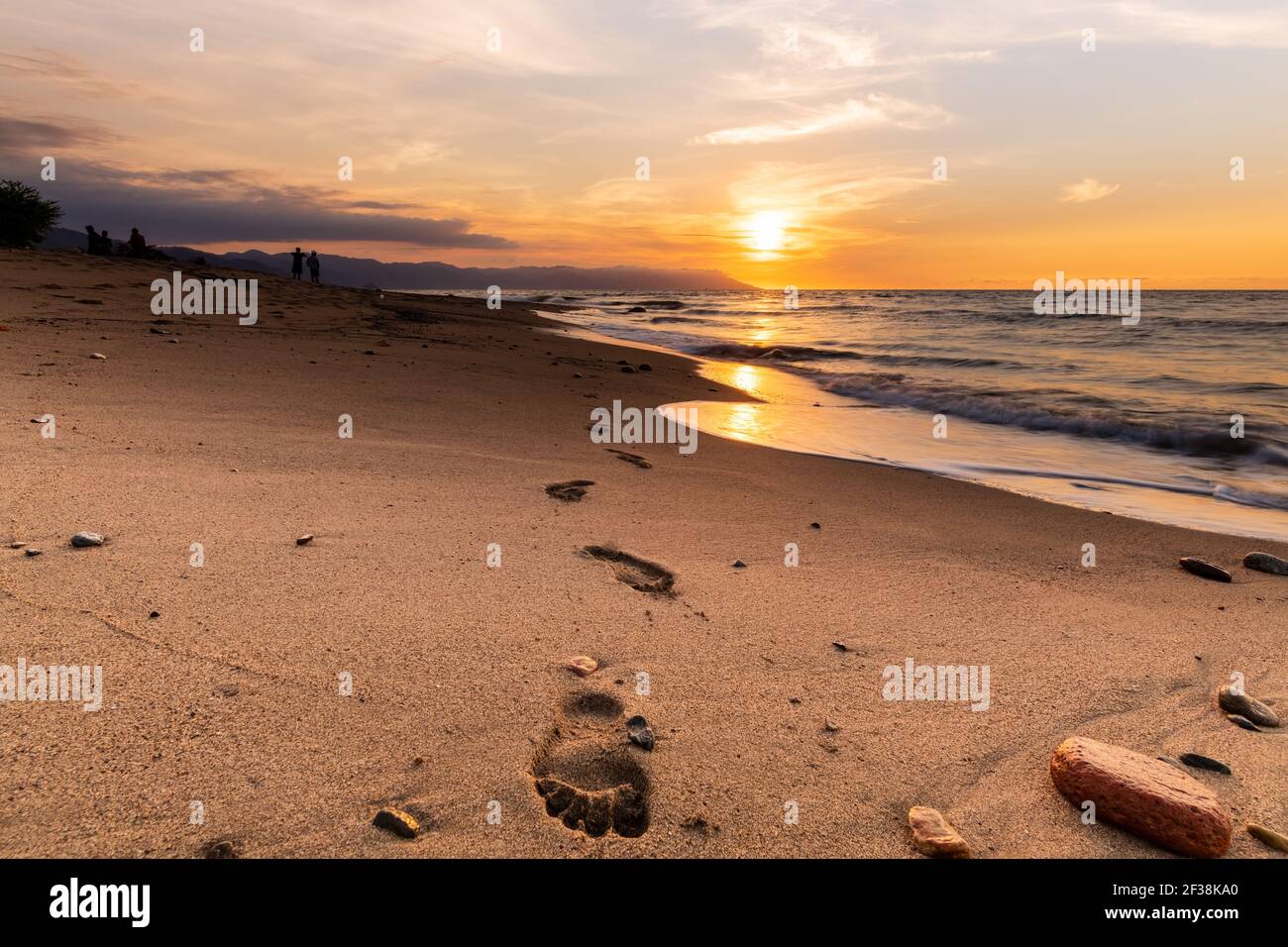 Impronte nell'oceano di sabbia Tramonto con la gente nel Sfondo Foto Stock