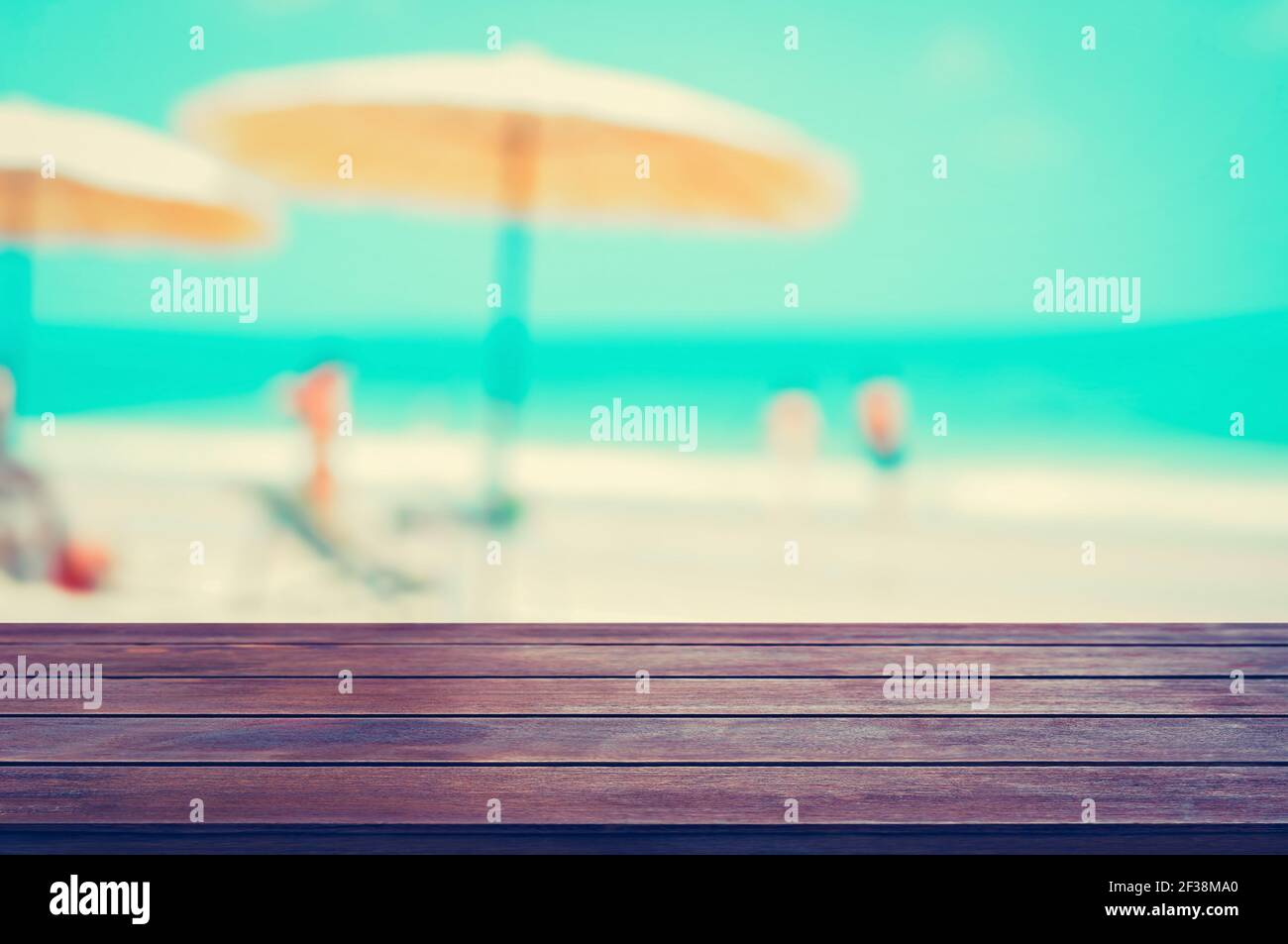 Tavolo in legno sullo sfondo della spiaggia sfocato, concetto di sfondo delle vacanze estive, tonalità vintage - può essere utilizzato per il montaggio o la visualizzazione dei vostri prodotti Foto Stock