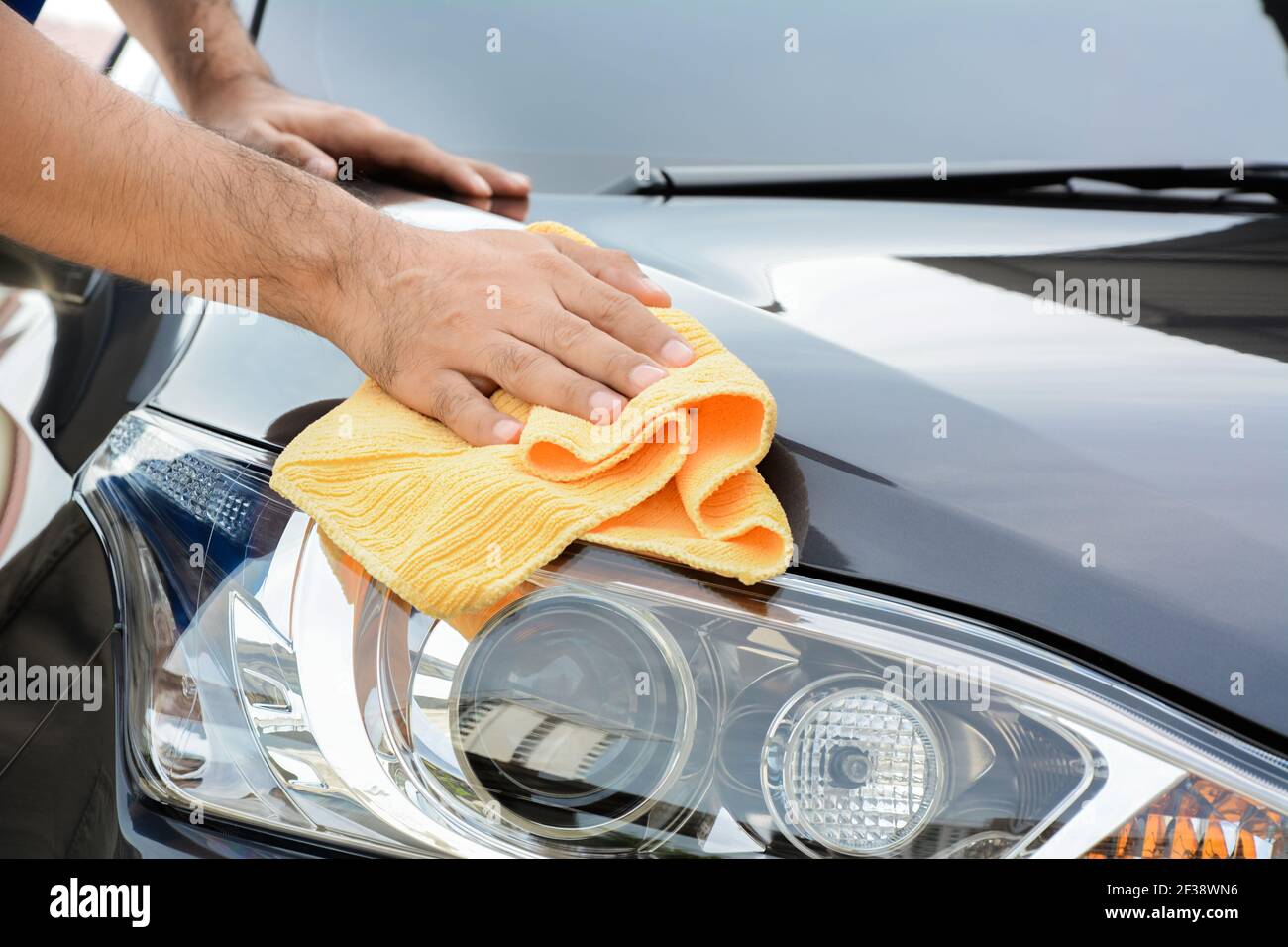 Un uomo che pulisce auto con panno in microfibra, auto che dettaglia (o valeting) concetto Foto Stock