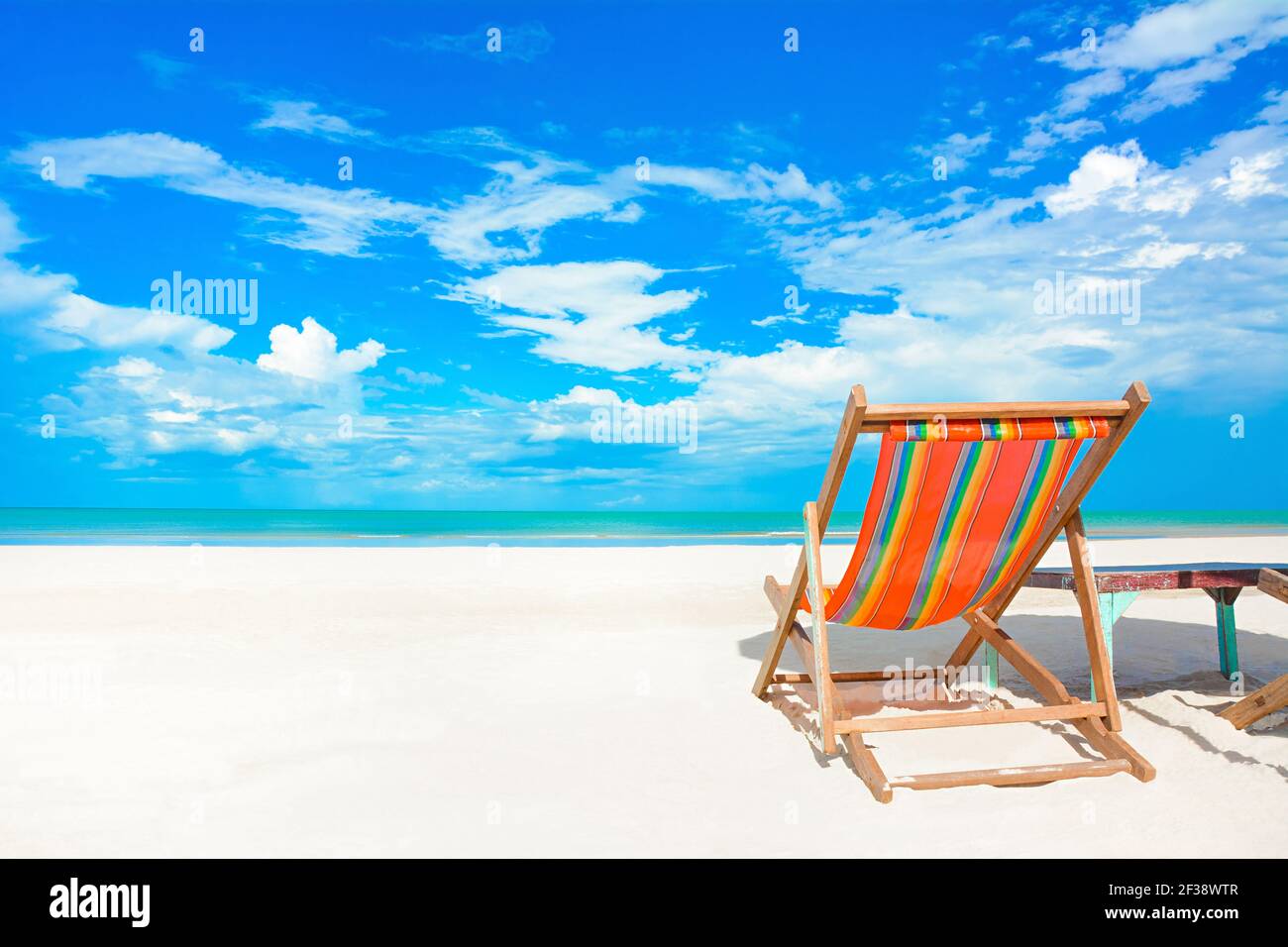 Sedia da spiaggia colorata su spiaggia di sabbia bianca in blu luminoso cielo sfondo - vacanze estive e concetti di vacanza Foto Stock