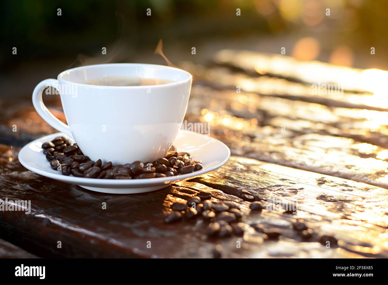 Caffè caldo nella tazza sul vecchio tavolo di legno con chicchi di caffè - effetto morbido e sfocato Foto Stock
