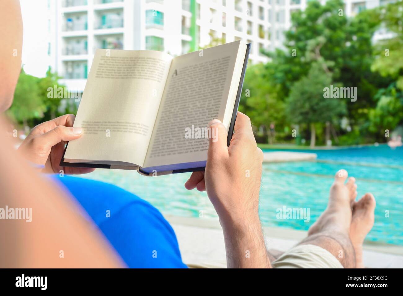 Un uomo che legge libro mentre si sdraiò in piscina Foto Stock