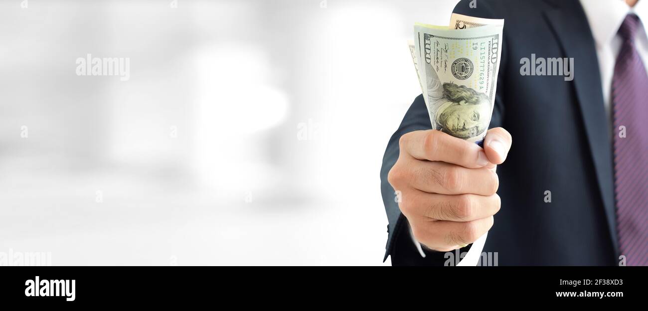 Businessman holding money, united states dollar (USD) fatture, su sfondo grigio sfocato bianco - finanziario e investimento concetto di sfondo panoramico Foto Stock