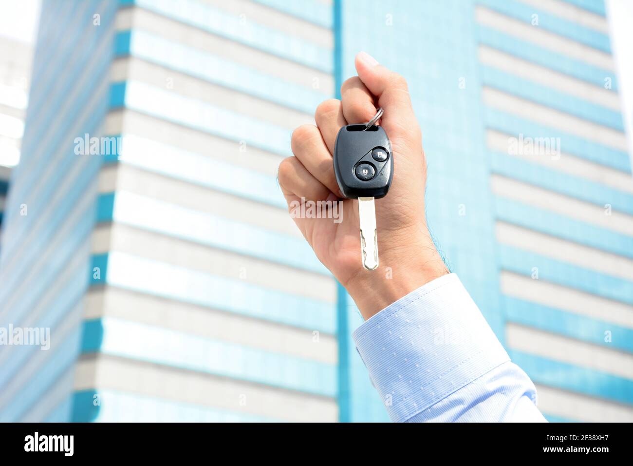 Tenere la chiave dell'auto con la mano sullo sfondo dell'edificio Foto Stock