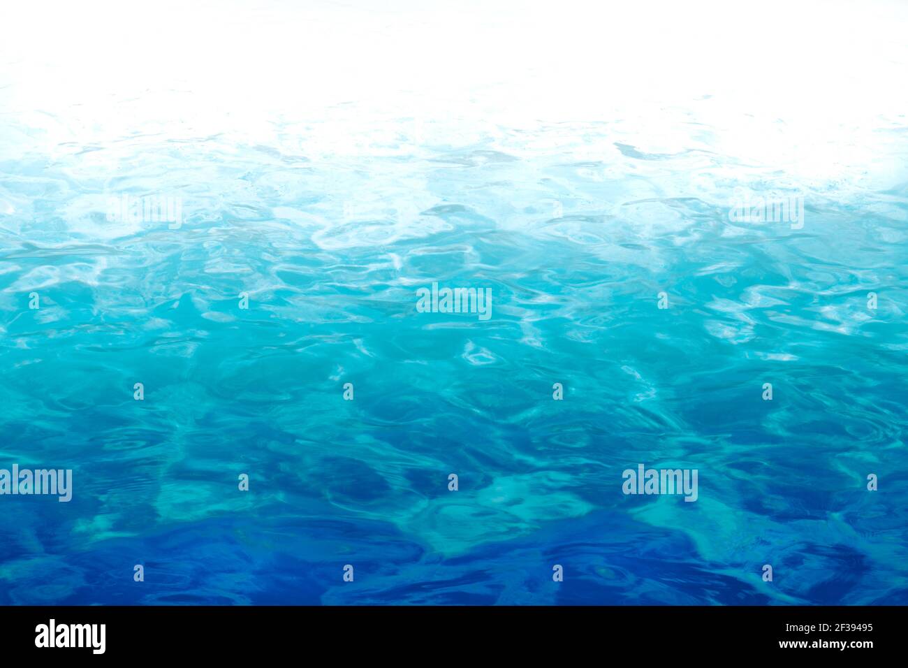 Acqua in una piscina con onde leggermente in movimento e riflessi del sole, gradiente da blu scuro a blu chiaro a bianco con copia-spazio Foto Stock