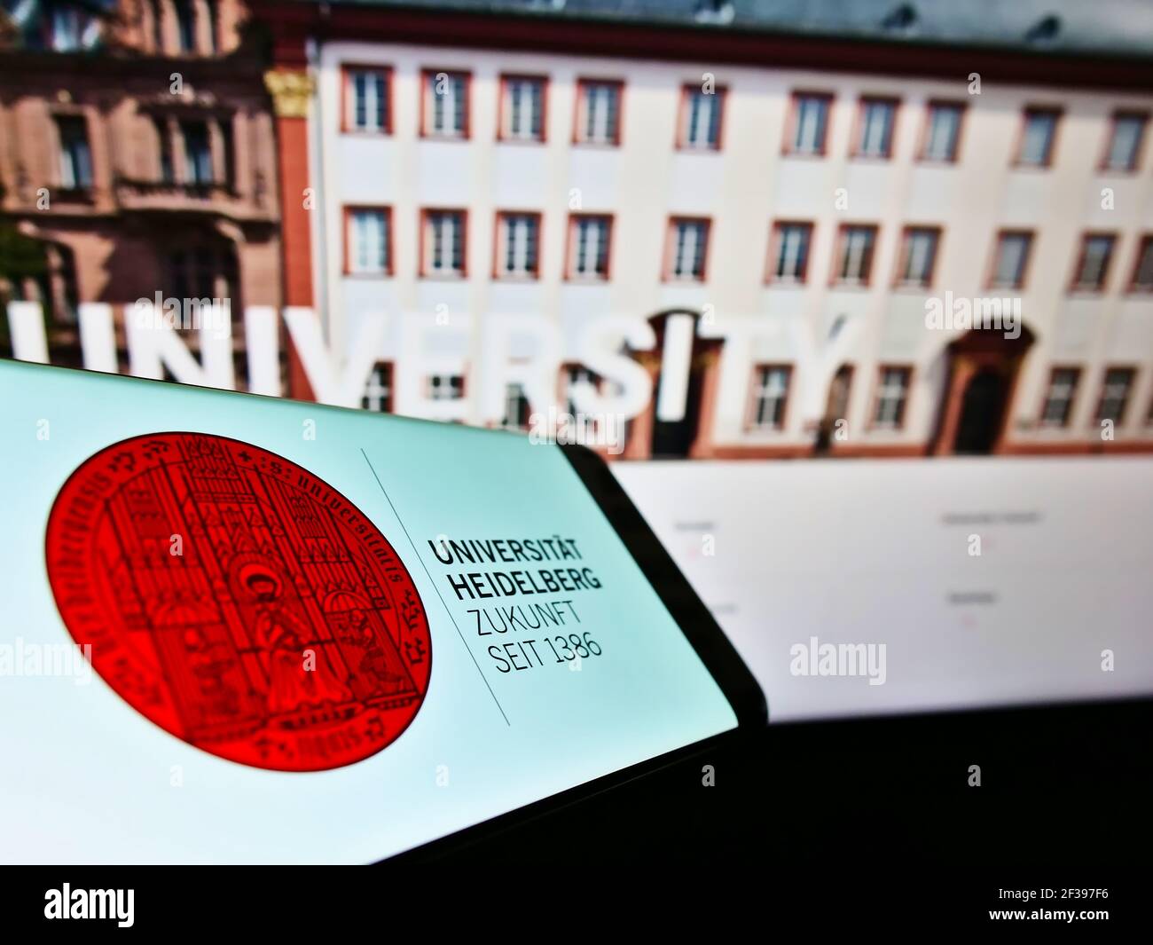 Smartphone con logo dell'istituto di istruzione tedesco University Heidelberg sullo schermo di fronte al sito Web. Mettere a fuoco il centro-destra del display del telefono. Foto Stock