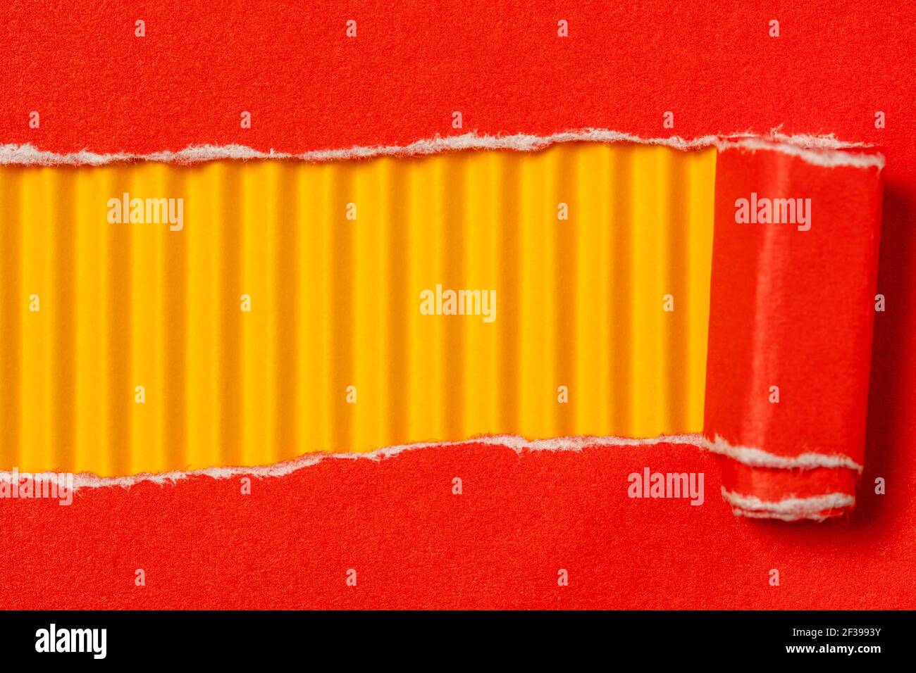 Carta rossa strappata per mostrare il pannello giallo ideale per la copia spazio Foto Stock