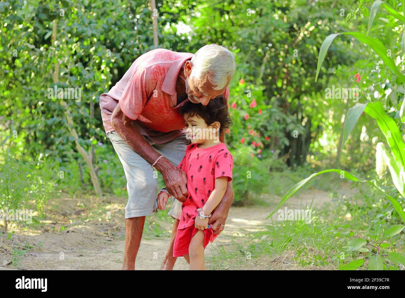 Nonno anziano di origine indiana che innalza con amore il nipote piccolo, india. Concetto per i ricordi dell'Infanzia, sorriso sul volto del bambino piccolo, Foto Stock