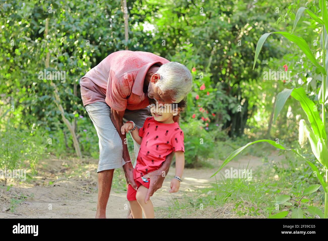 Nonno anziano di origine indiana che tiene amorevolmente il nipote più giovane, india. Concetto per i ricordi dell'Infanzia, sorride sul volto del bambino piccolo Foto Stock