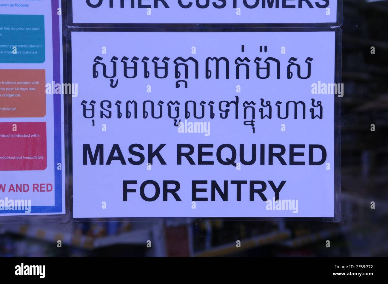 Durante un focolaio di COVID - 19, il governo cambogiano ha imposto un mandato mascherante. Un cartello bilingue all'ingresso di un negozio di alimentari che avverte la gente di indossare maschere / rivestimenti durante la pandemia del coronavirus. Phnom Penh, Cambogia. 15 Marzo 2021. © Kraig Lieb Foto Stock