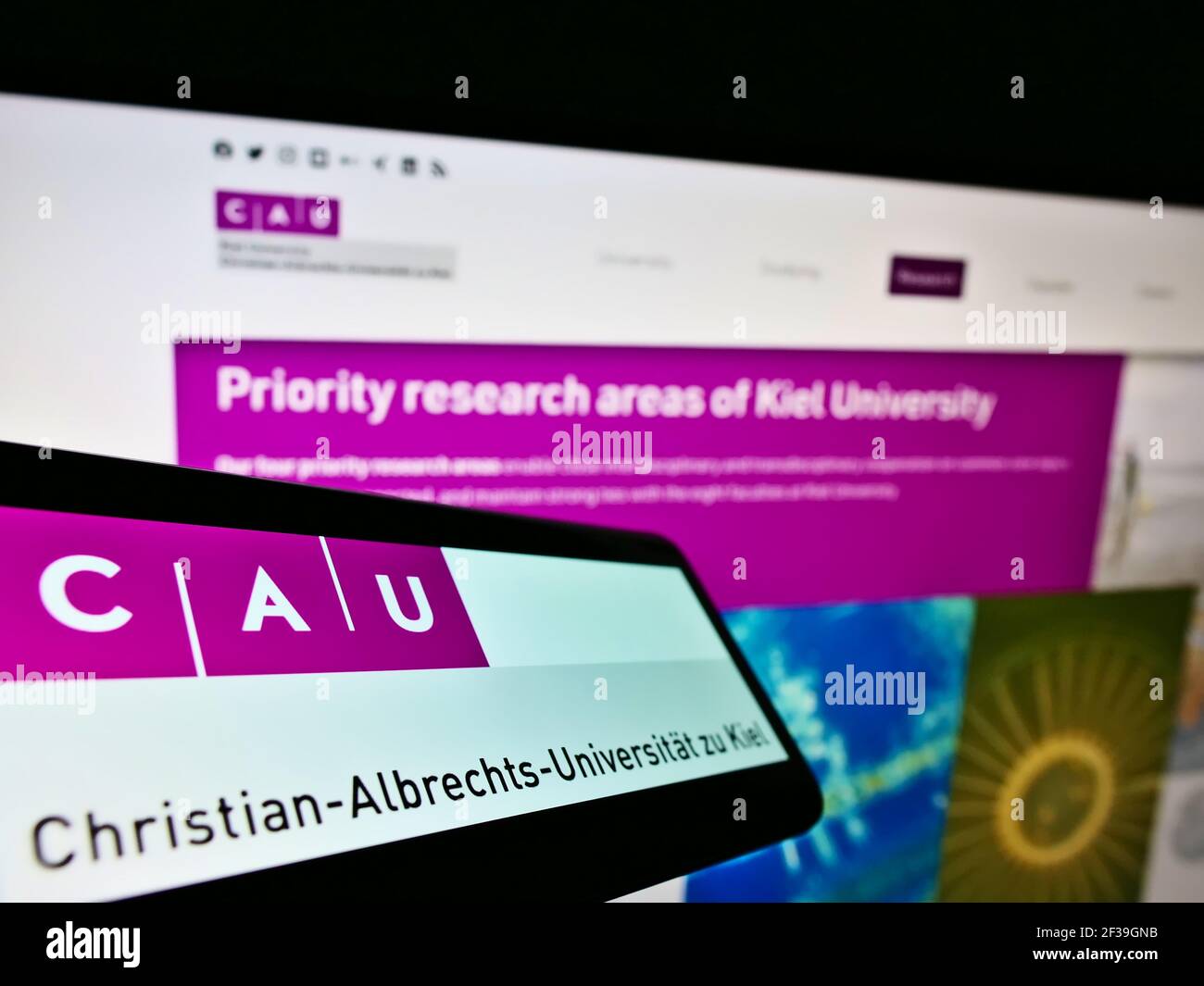 Cellulare con logo dell'istituto di istruzione tedesco Università di Kiel sullo schermo davanti alla pagina web. Mettere a fuoco il centro-destra del display del telefono. Foto Stock