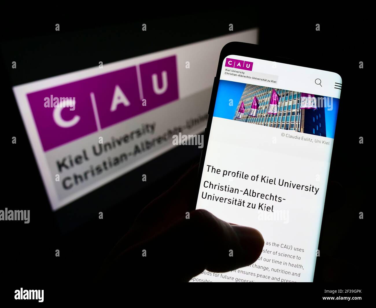 Persona che tiene il cellulare con il sito web dell'istituto tedesco di istruzione Università di Kiel sullo schermo di fronte al logo. Mettere a fuoco il centro del display del telefono. Foto Stock