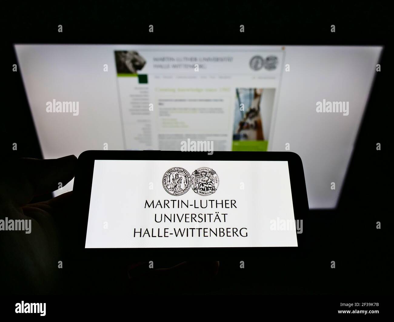 Persona che detiene smartphone con logo tedesco Martin-Luther-Universität Halle-Wittenberg sullo schermo di fronte al sito web. Mettere a fuoco il display del telefono. Foto Stock