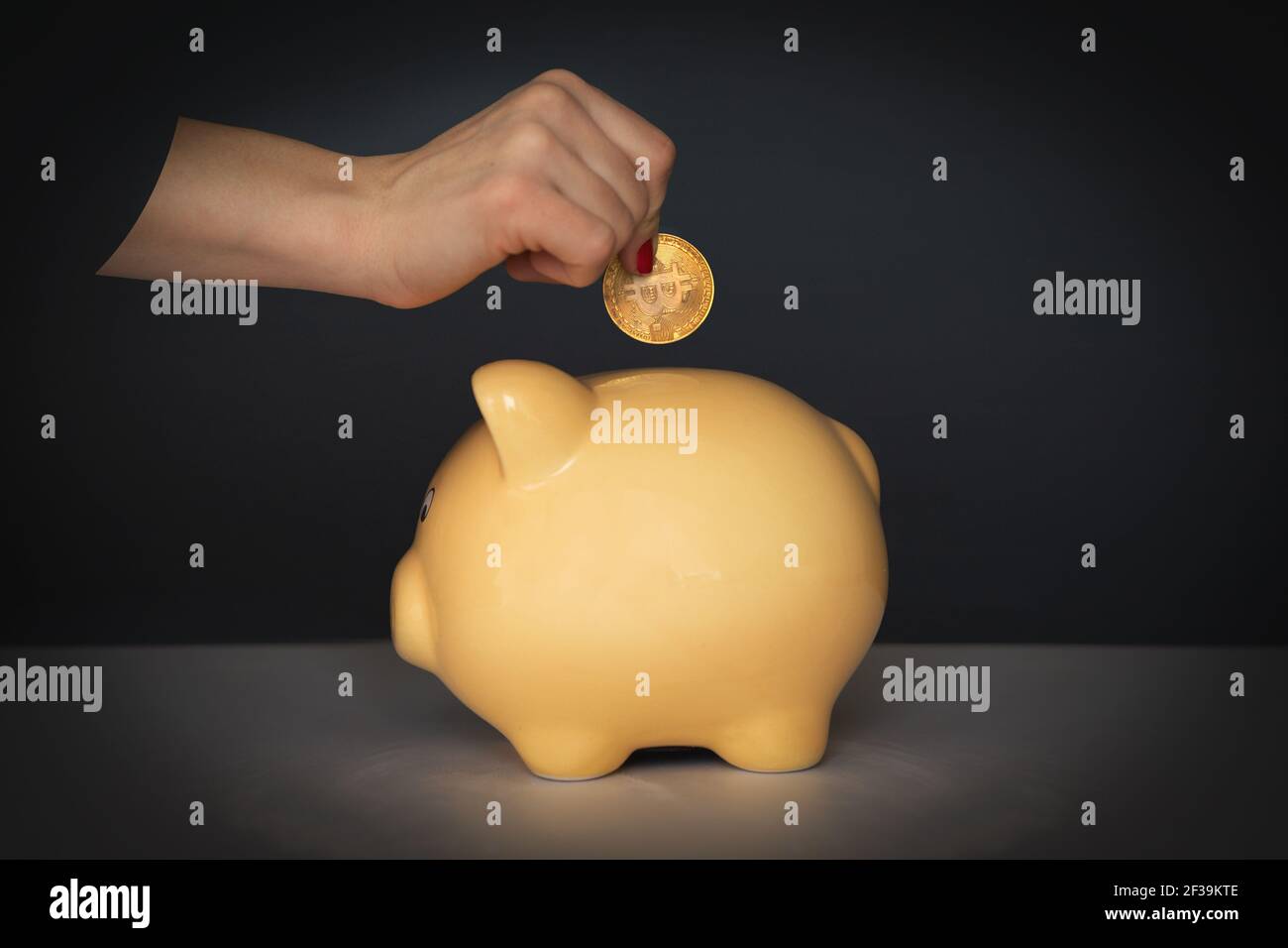 Crop femminile irriconoscibile mettere moneta in giallo piggy bank mentre mostrare il concetto di investimento e risparmio di denaro Foto Stock