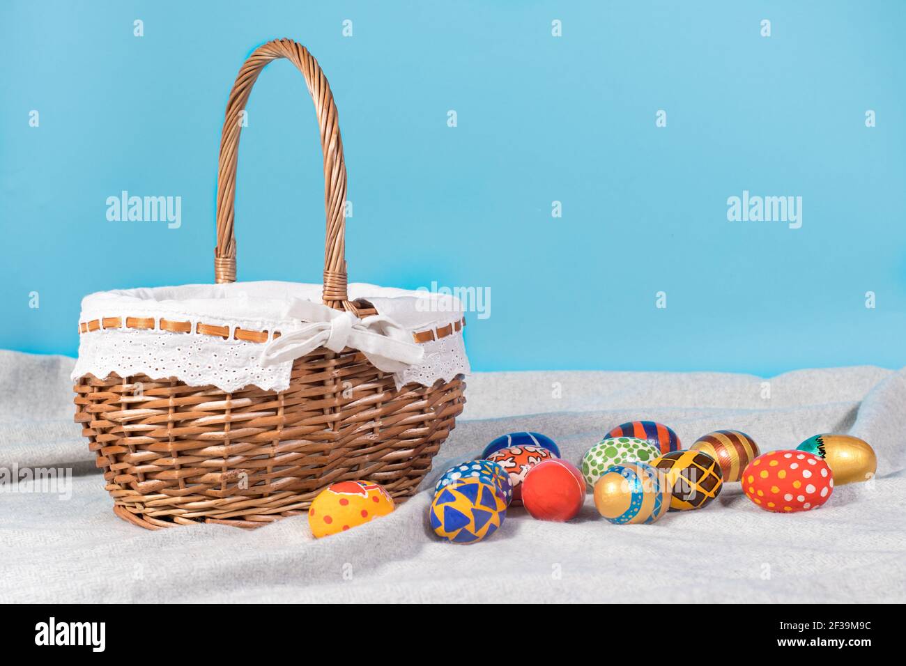 Delicata foto di Pasqua minimalista - un cesto di vimini e dipinto uova su uno sfondo blu copia lo spazio con un posiziona per il testo Foto Stock