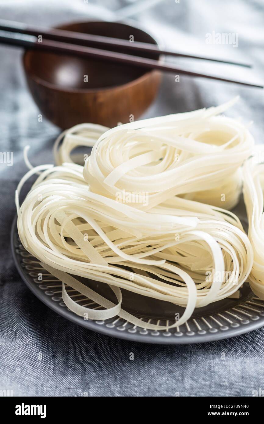 Tagliatelle di riso bianco essiccato. Pasta cruda. Tagliatelle non cotte sul piatto. Foto Stock