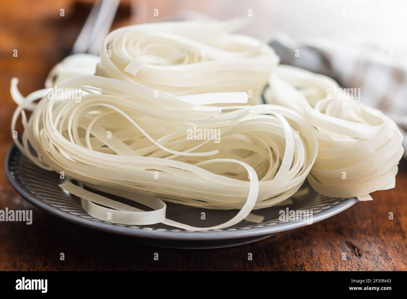 Tagliatelle di riso bianco essiccato. Pasta cruda. Tagliatelle non cotte sul piatto. Foto Stock