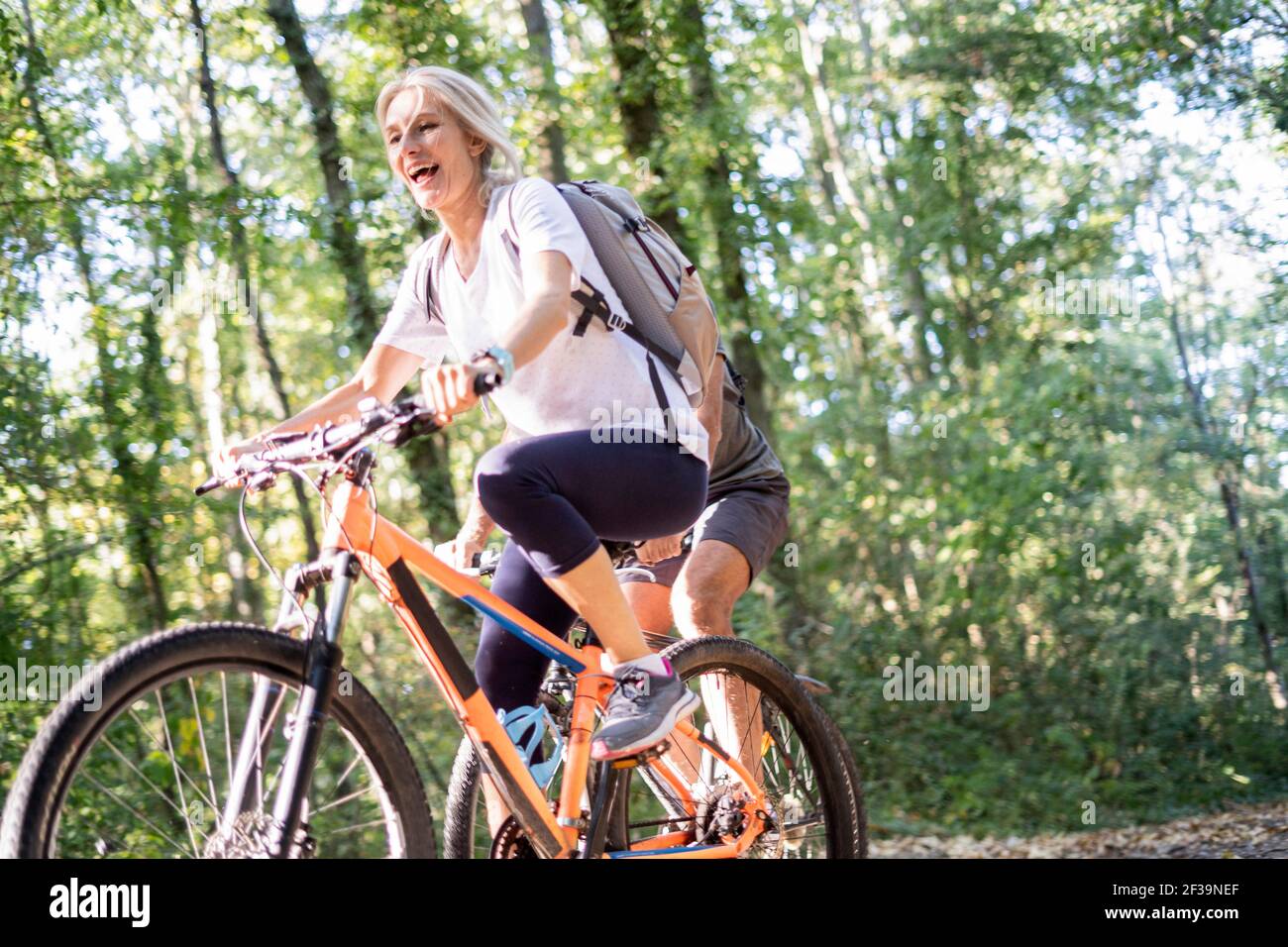 Vista ad angolo basso delle coppie mature che pedalano in bicicletta nella foresta Foto Stock