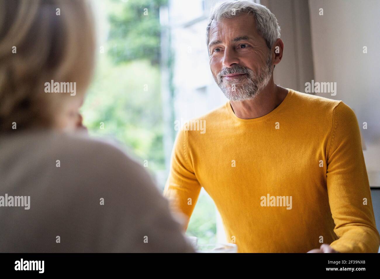 Uomo maturo sorridente che guarda sua moglie a casa Foto Stock