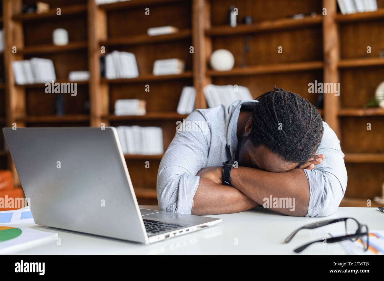 Afro-americano stanco privato uomo d'affari sensazione di mancanza di sonno avendo pisolino sul posto di lavoro, nero inquieto imprenditore disperato da fallimento o debito, depresso investitore disperato in caso di fallimento Foto Stock