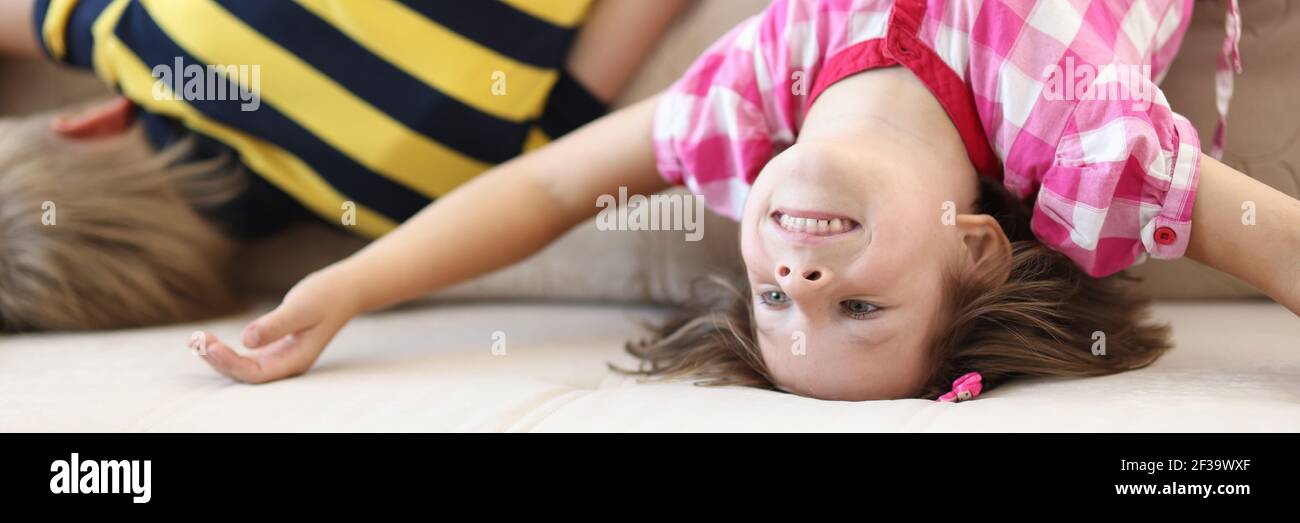 Divertente bambino stare capovolto sul divano e giocare. Foto Stock