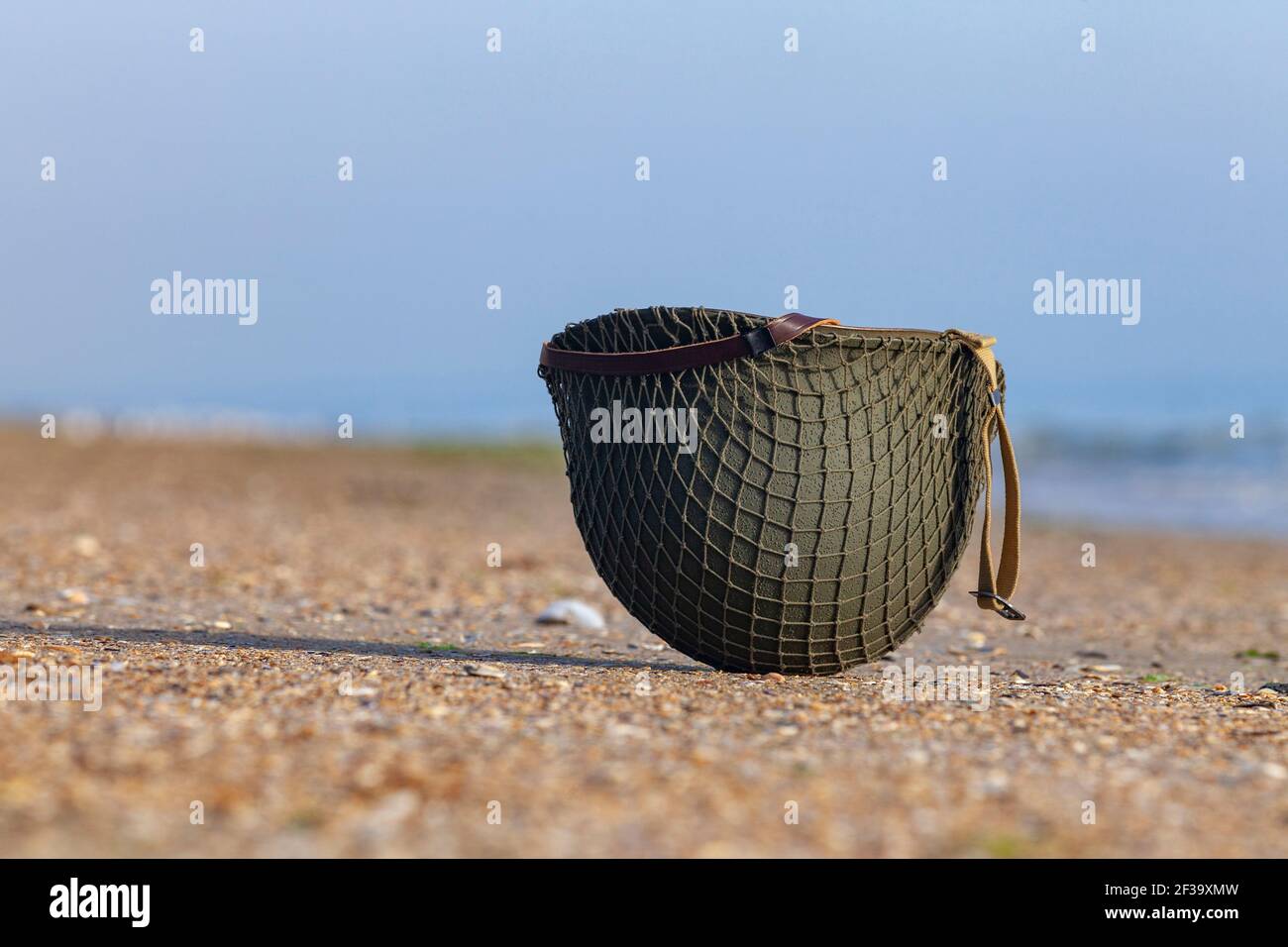 Casco americano della seconda Guerra Mondiale su una spiaggia del Sbarco in Normandia Foto Stock