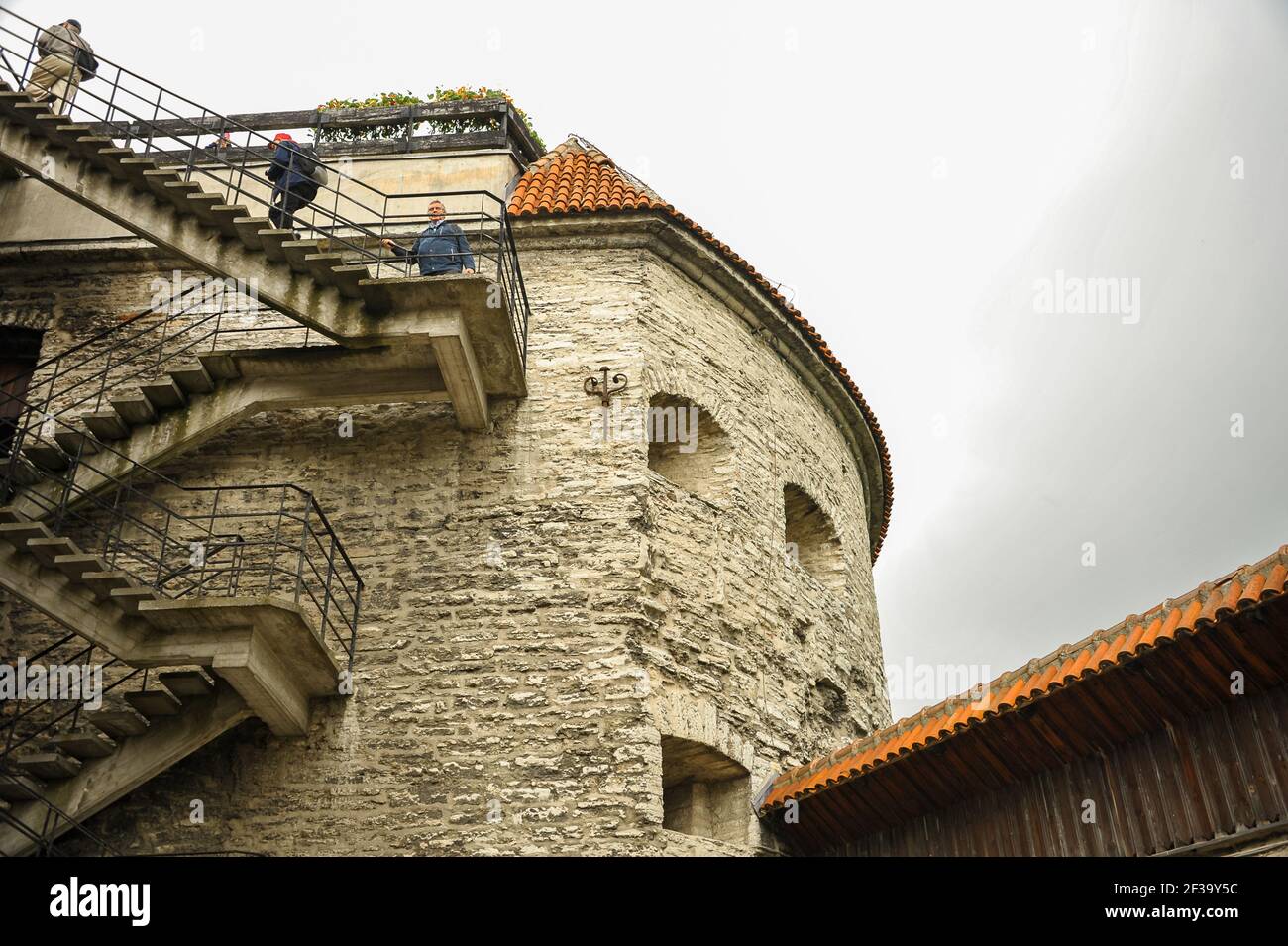 Tallinn, Estonia - Luglio 2015: Persone che arrampicano scalinata esterna sulle mura medievali della città. Vecchia torre di guardia in pietra con sfondo grigio del cielo Foto Stock Tallinn, Estonia - Luglio 2015: Persone che arrampicano scalinata esterna sulle mura medievali della città. Vecchia torre di guardia in pietra con sfondo grigio del cielo Foto Stock