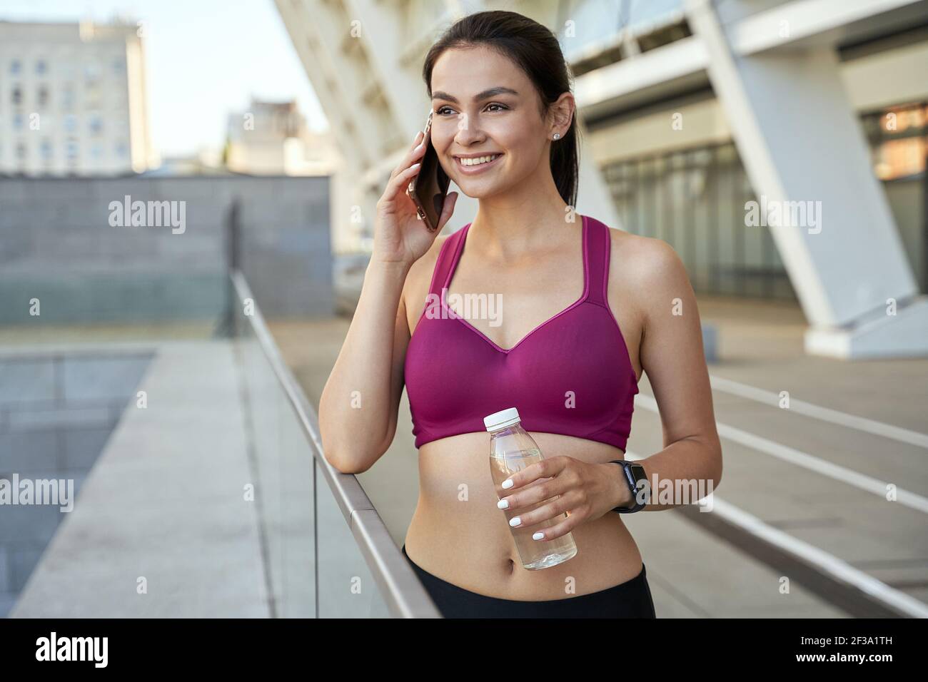 Felice giovane atletica utilizzando il telefono cellulare all'aperto Foto Stock