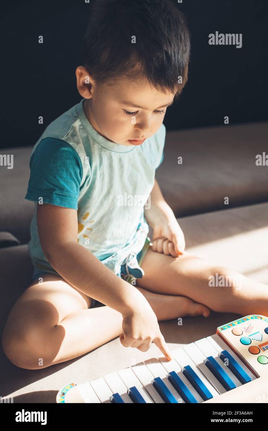 Caucasico ragazzo sta suonando il piano sul pavimento scoprendo nuovo hobby Foto Stock