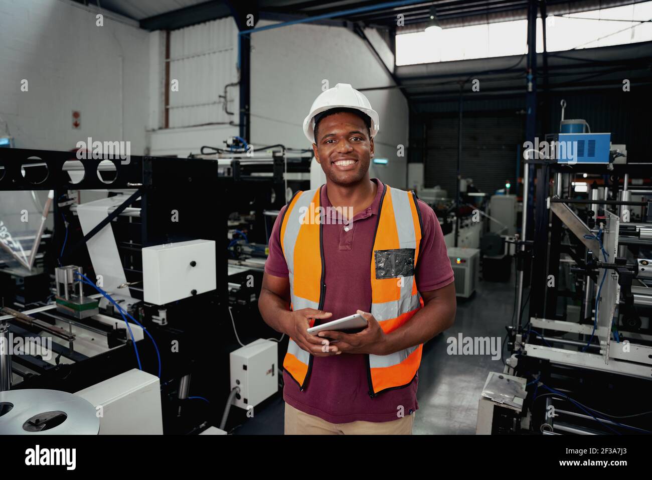 Ritratto di un felice ingegnere industriale in piedi in fabbrica con tablet intelligente Foto Stock