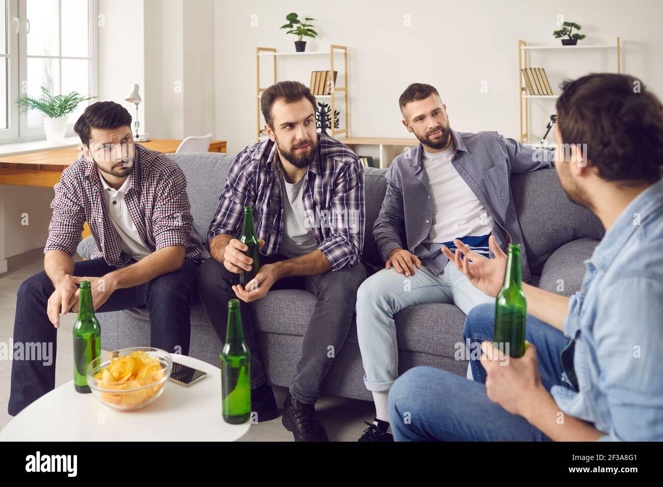Gli amici di sesso maschile bevono birra e stanno conversando piacevolmente, trascorrendo un po' di tempo insieme. Foto Stock