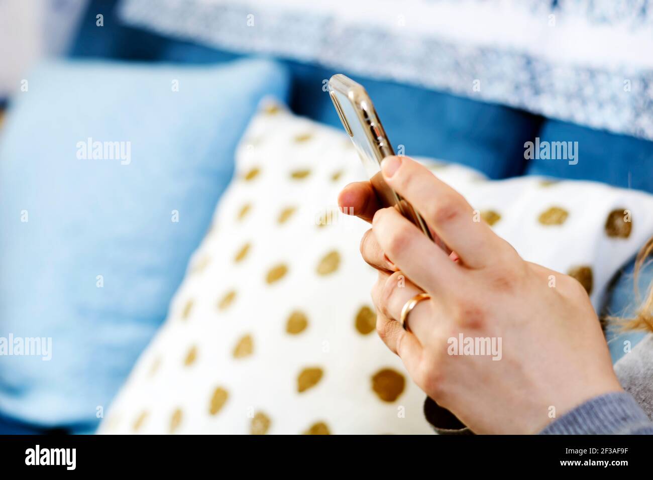 le mani di una giovane bruna caucasica mentre si tiene uno smartphone digitando sul touch screen. Tecnologia e connessione mobile. Foto Stock