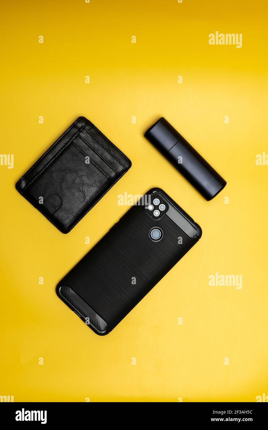 portafoglio in pelle per smartphone e sigaretta elettronica su sfondo giallo Foto Stock