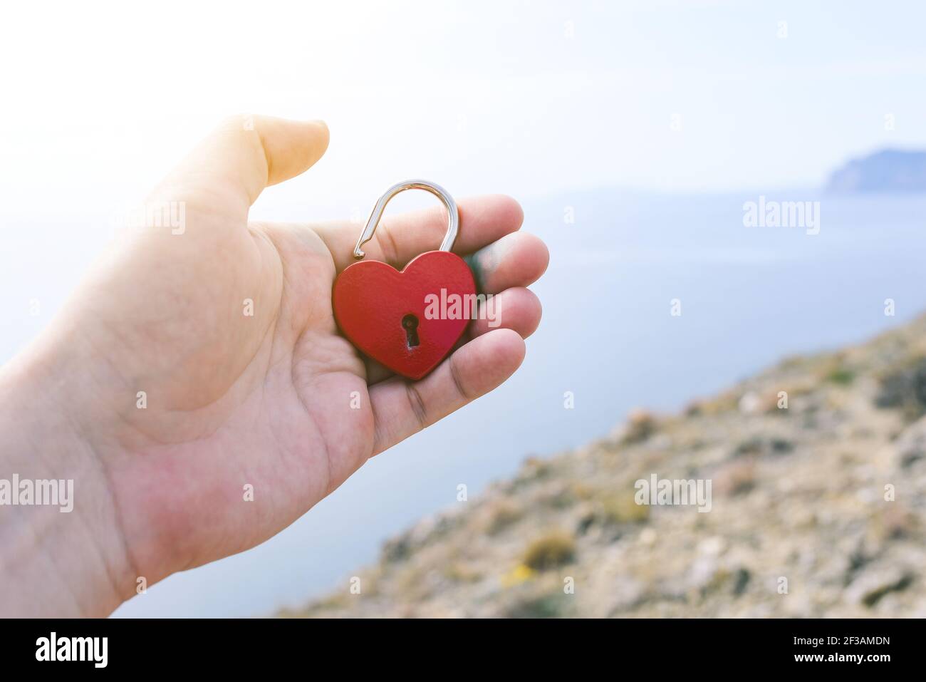 Mano maschile che tiene un castello d'amore sullo sfondo del mare. Aprire il blocco piccolo. Relazione, amore e datazione concetto. Cercare una coppia per creare un Foto Stock