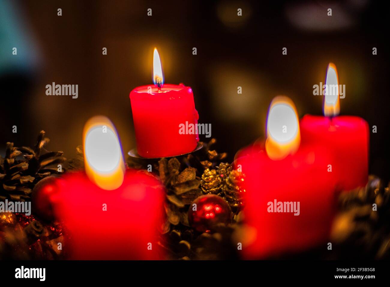 Low-key studio girato di una bella corona di avvento con baubles e una candela rossa che brucia Foto Stock