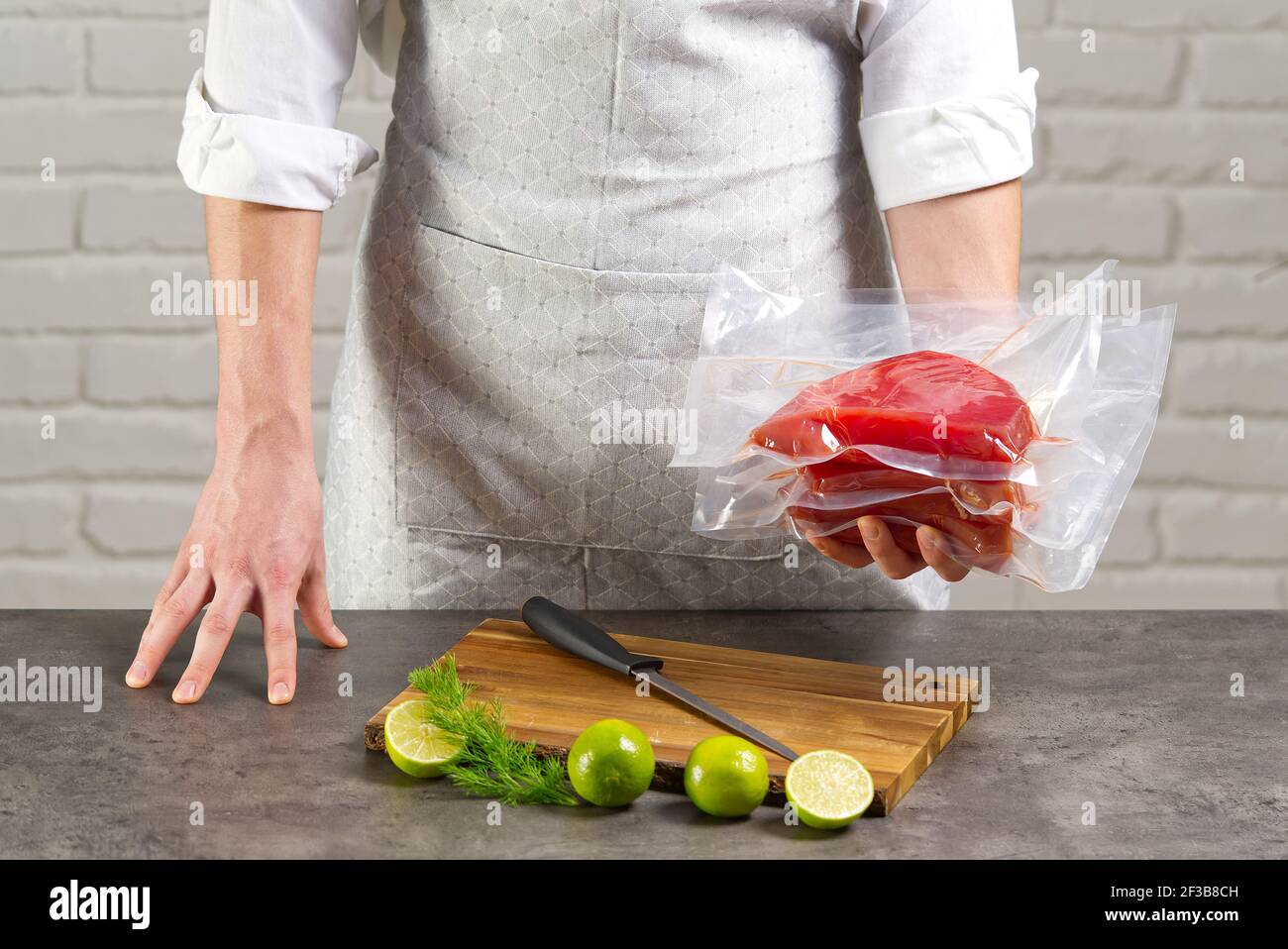 un cuoco o un venditore in un'azienda del mercato del pesce una bistecca di tonno rosso confezionata in un sacchetto sottovuoto Foto Stock