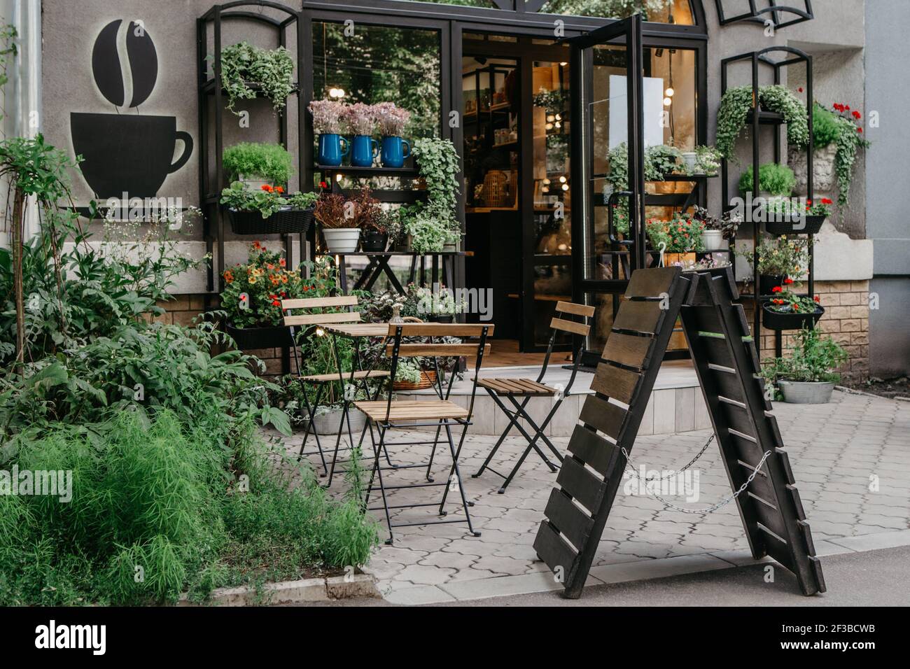 Eco cafe moderno con stile naturale per una pausa in città, negozio di fiori di moda, interni esterni Foto Stock