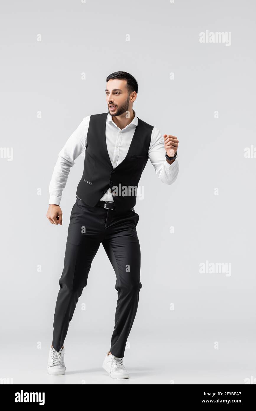 vista completa dell'uomo arabo con pantaloni neri e. gilet in esecuzione su  grigio Foto stock - Alamy