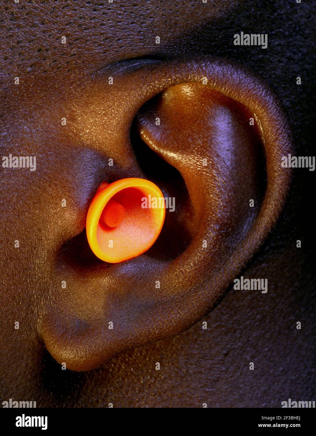 l'orecchio di un uomo con un tappo auricolare in posizione utilizzato come protezione dai suoni forti Foto Stock