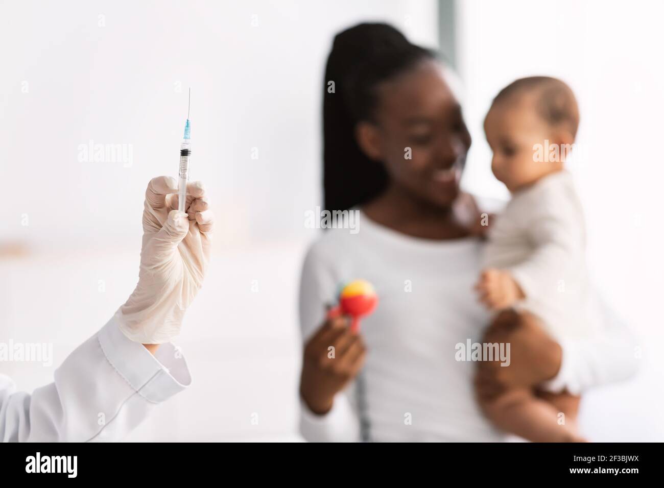 Madre afroamericana che tiene il bambino per la vaccinazione Foto Stock