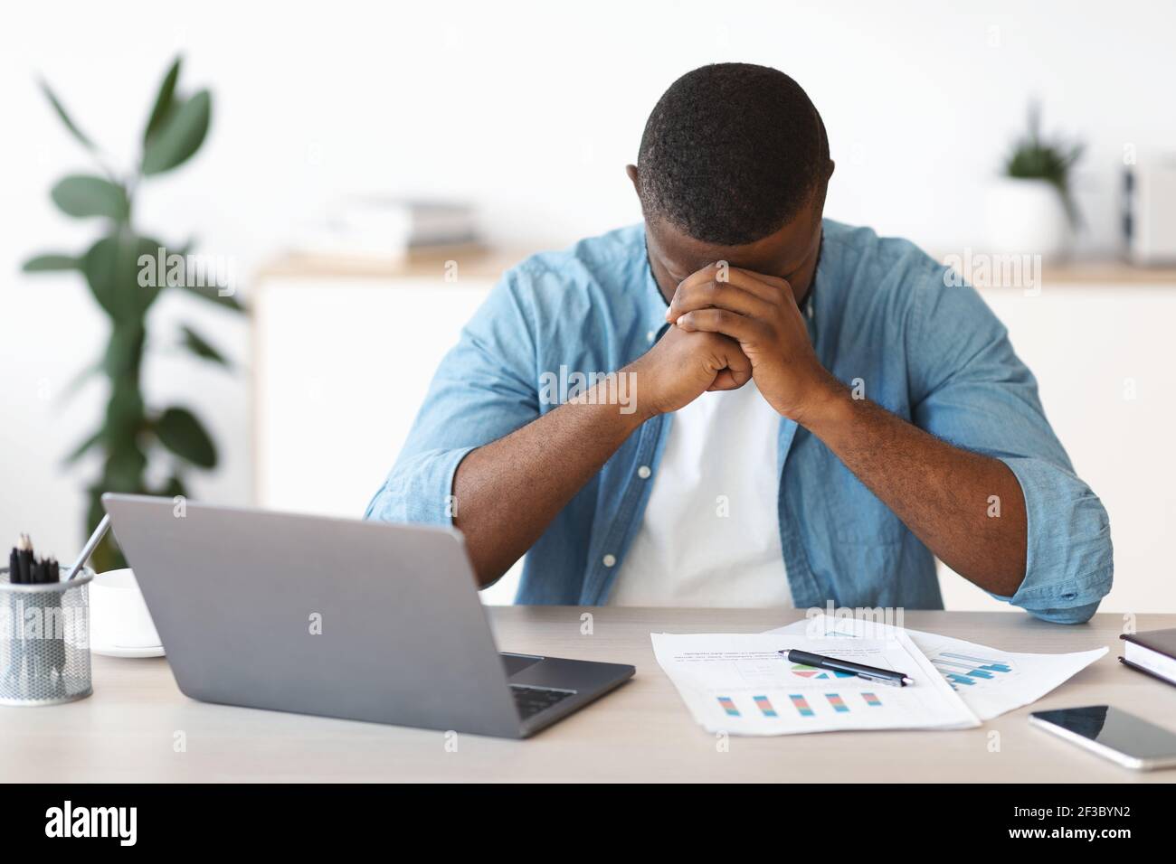 Depresso imprenditore afro-americano che ha problemi al lavoro Foto Stock
