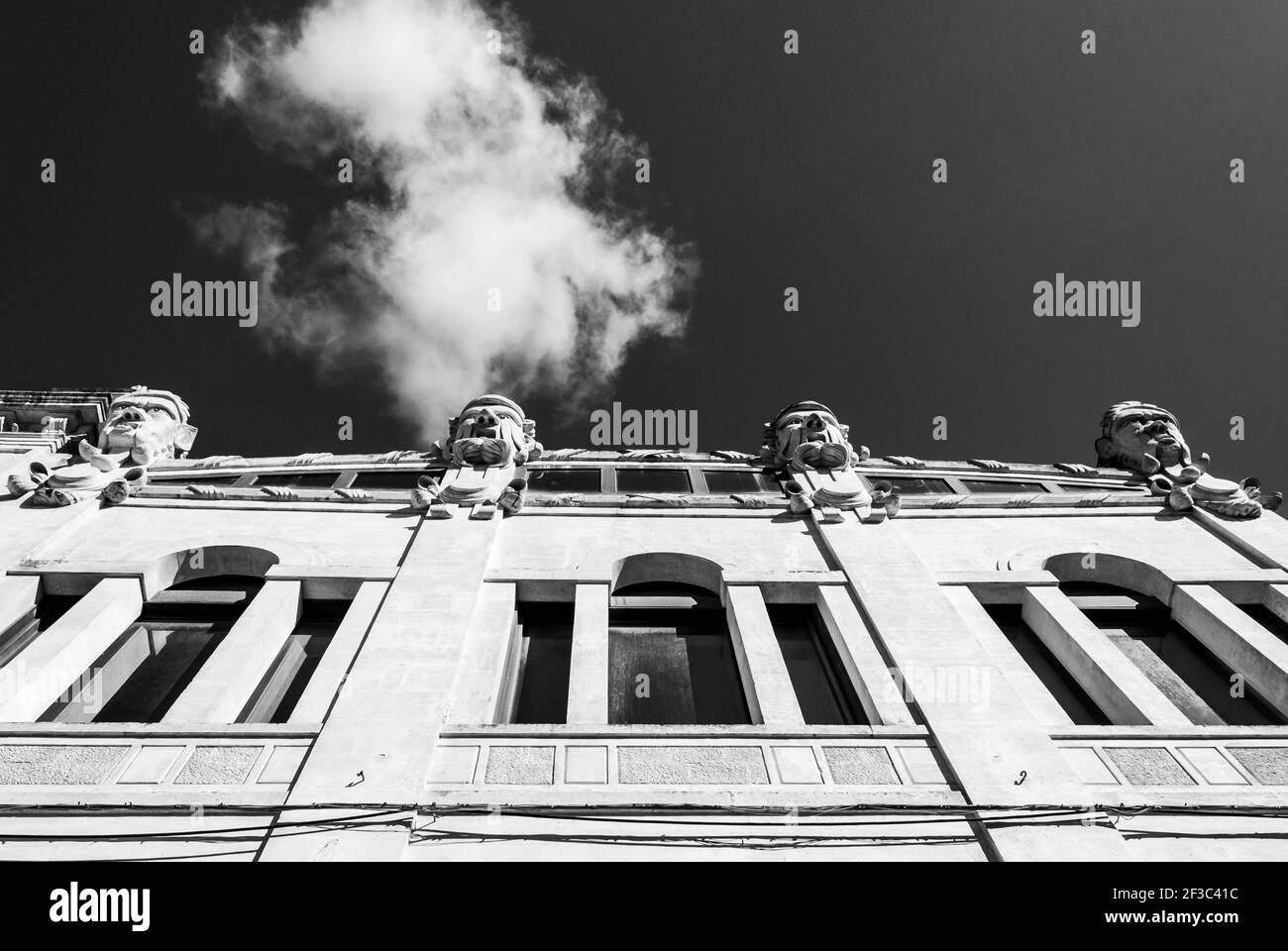 Una foto monocromatica a basso angolo di maschere decorative di un edificio nel centro storico di Modica, Italia Foto Stock