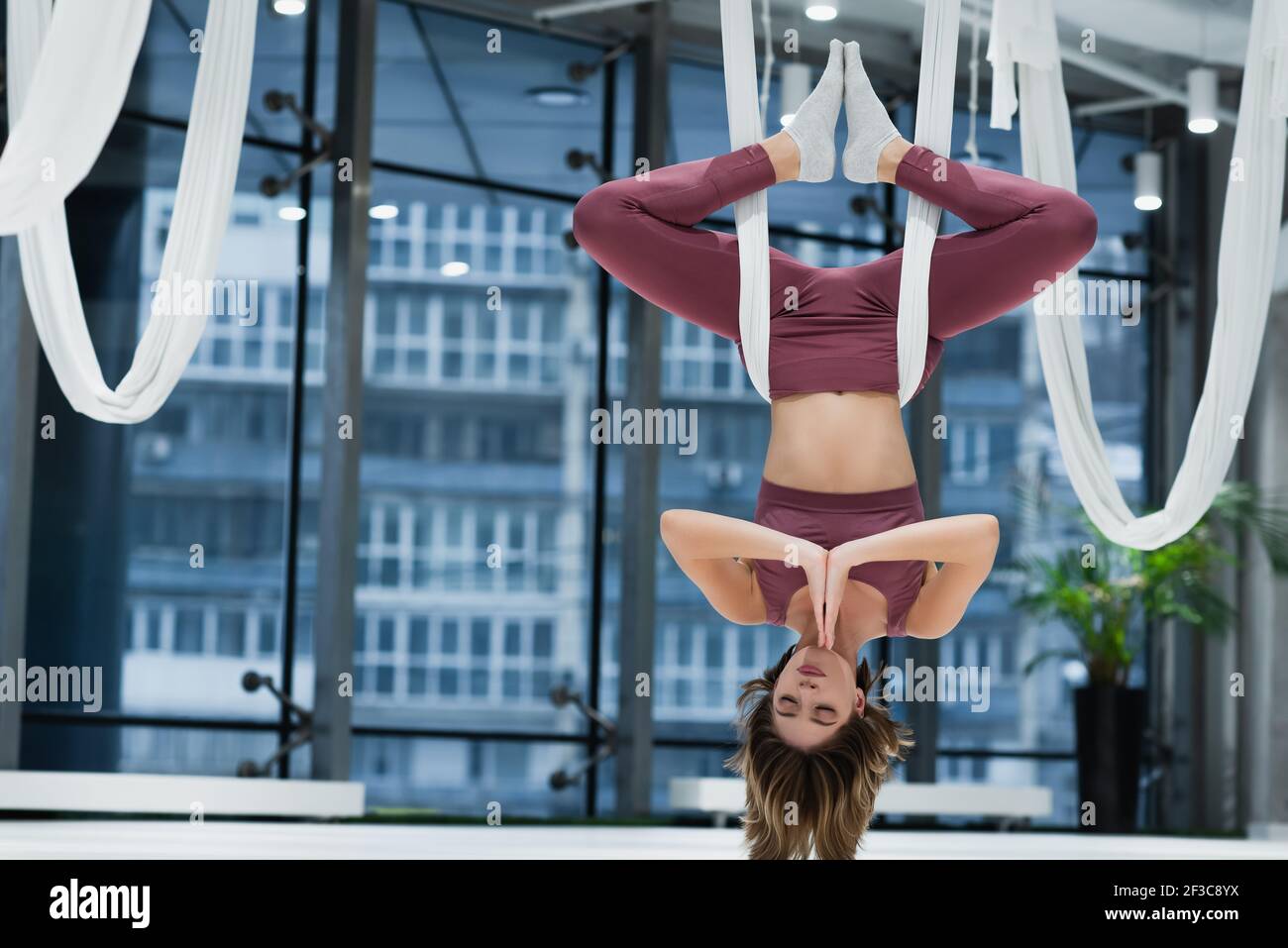 Giovane sportiva appesa al volo cinghie yoga in centro fitness Foto Stock