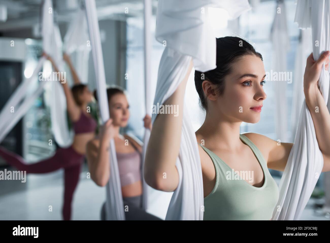 bella sportiva che allunga le braccia con cinturino da yoga aereo in forma fisica centro Foto Stock