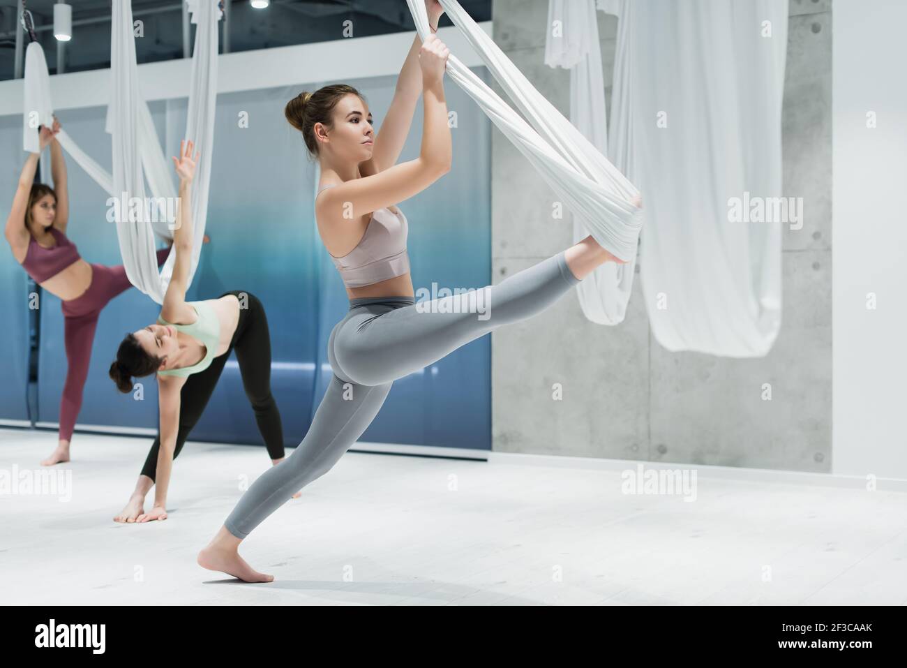 Donna che lavora con le cinghie durante lo yoga della mosca in forma fisica centro Foto Stock
