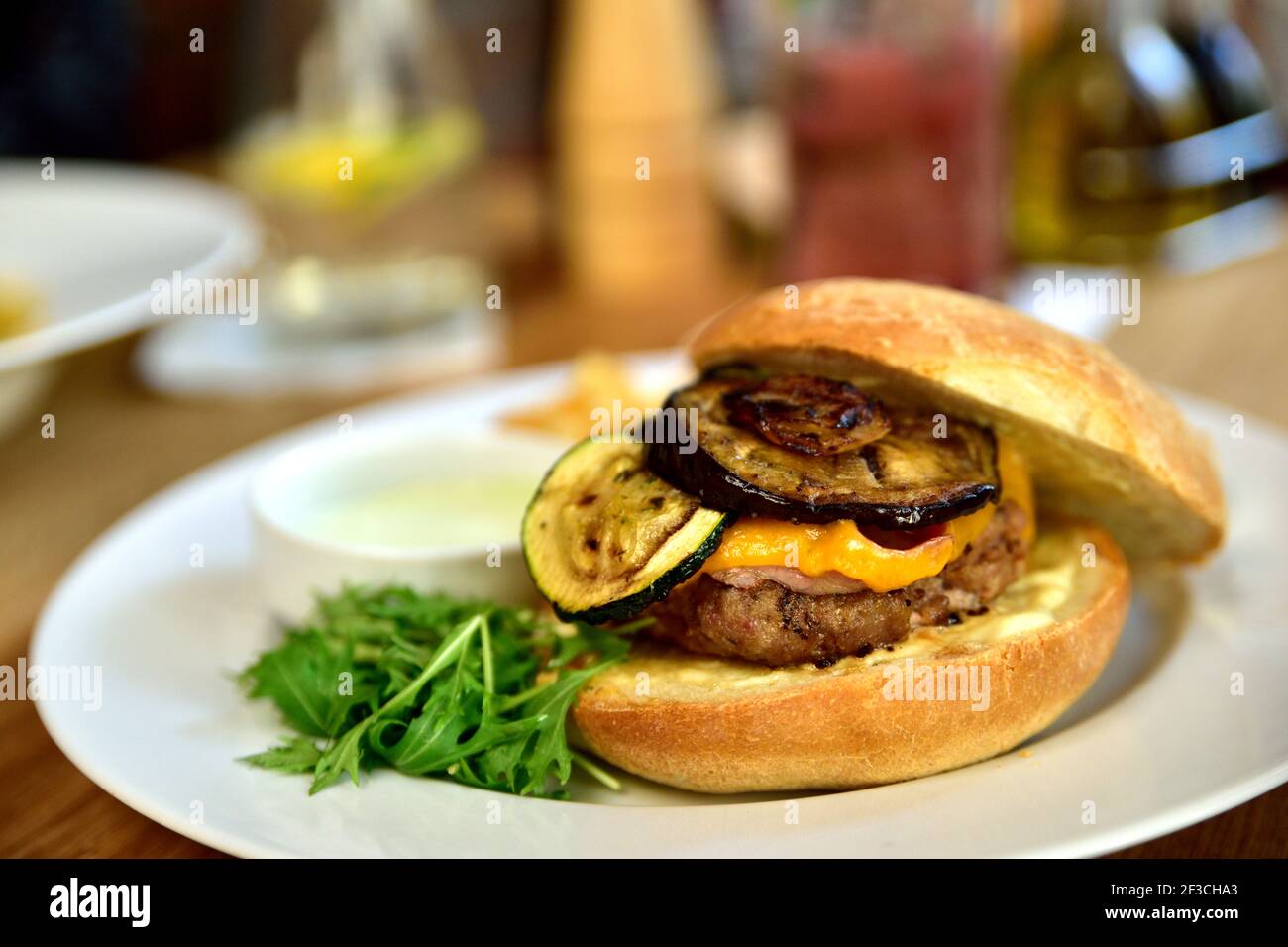 Cibo da ristorante con ingredienti freschi - hamburger con formaggio cheddar, zucchine, fette di patate e salsa tartara Foto Stock