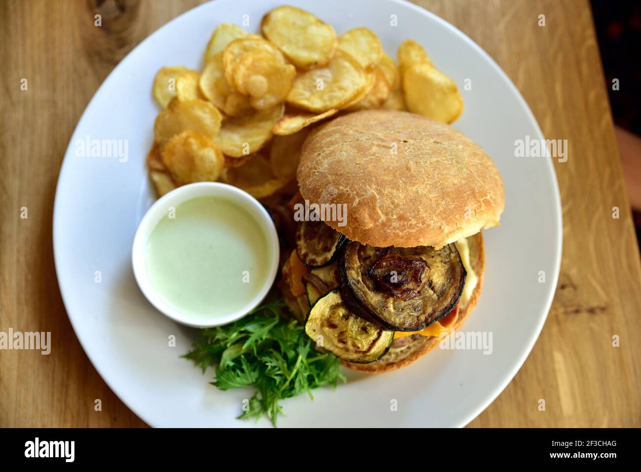 Cibo da ristorante con ingredienti freschi - hamburger con formaggio cheddar, zucchine, fette di patate e salsa tartara Foto Stock