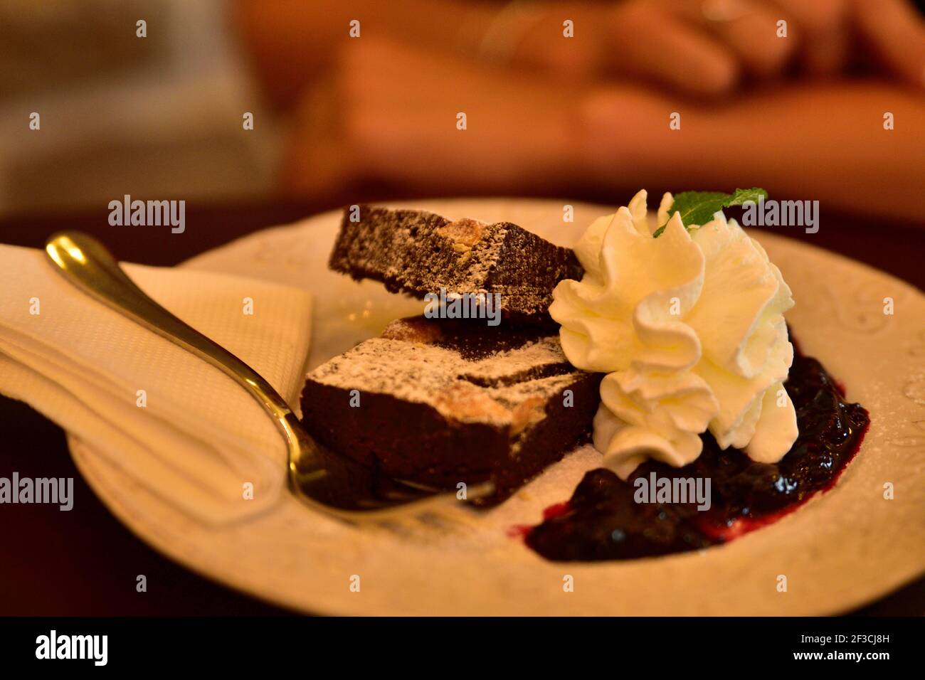 Cibo da ristorante con ingredienti freschi - torta al cioccolato con montata panna e caffè sullo sfondo Foto Stock