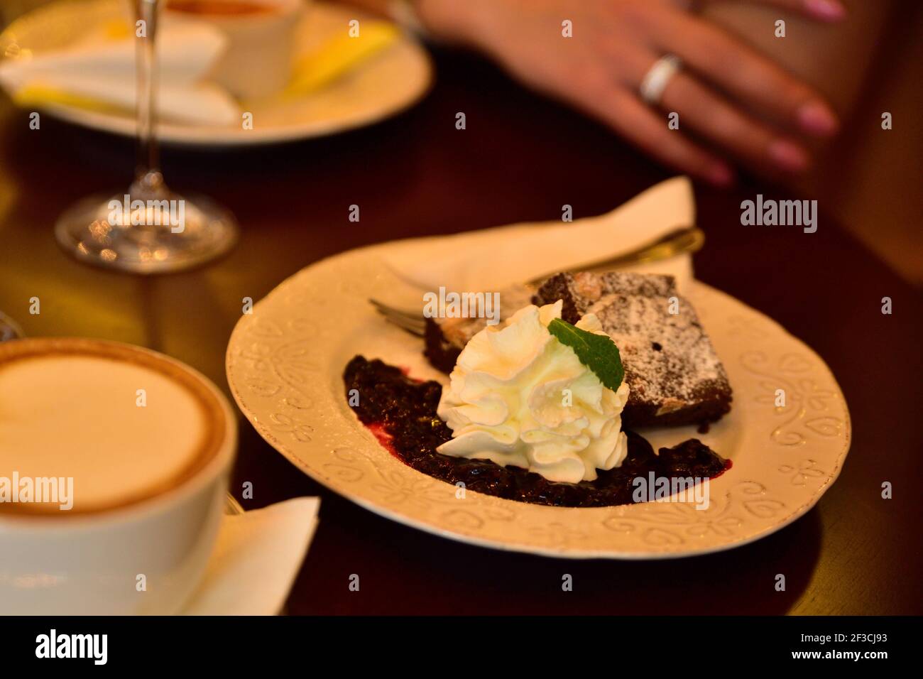 Cibo da ristorante con ingredienti freschi - torta al cioccolato con montata panna e caffè sullo sfondo Foto Stock
